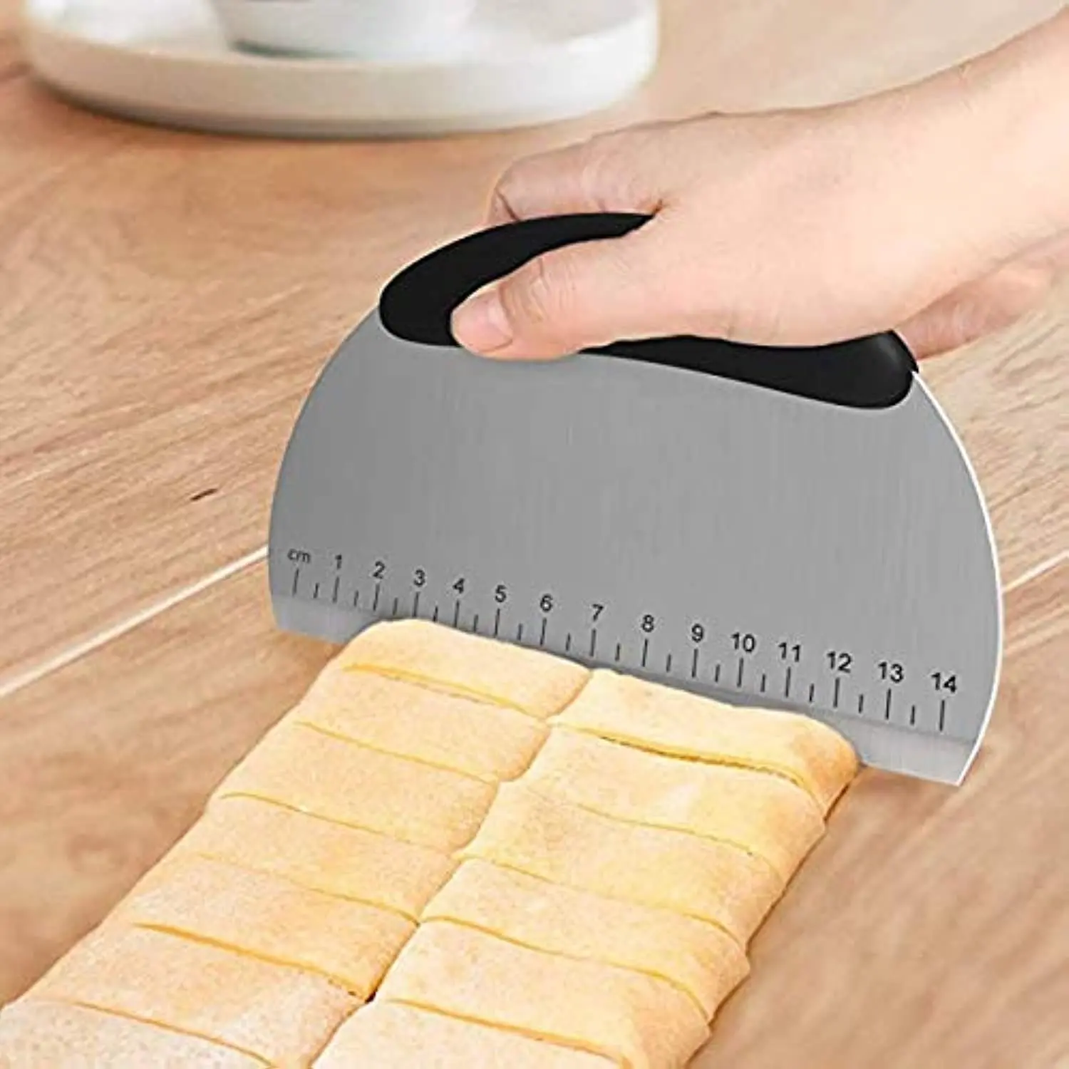 This stainless steel bench scraper and dough cutter features a comfortable non-slip handle and a measuring scale for easy and precise cutting of pizza dough, pastries, and cake.