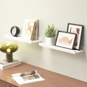 This set of two white floating shelves with a front lip provides sturdy and stylish wall-mounted storage for displaying pictures, books, plants, and decorative items in any room.