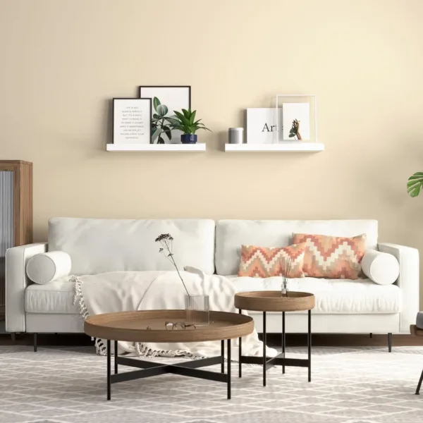 This set of two white floating shelves with a front lip provides sturdy and stylish wall-mounted storage for displaying pictures, books, plants, and decorative items in any room.