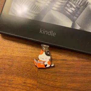 This 7-pack of bookish cat USB-C dust plugs protects your Kindle, iPhone 15, and other devices from dust and dirt while adding a charming touch.