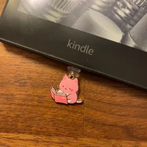 This 7-pack of bookish cat USB-C dust plugs protects your Kindle, iPhone 15, and other devices from dust and dirt while adding a charming touch.