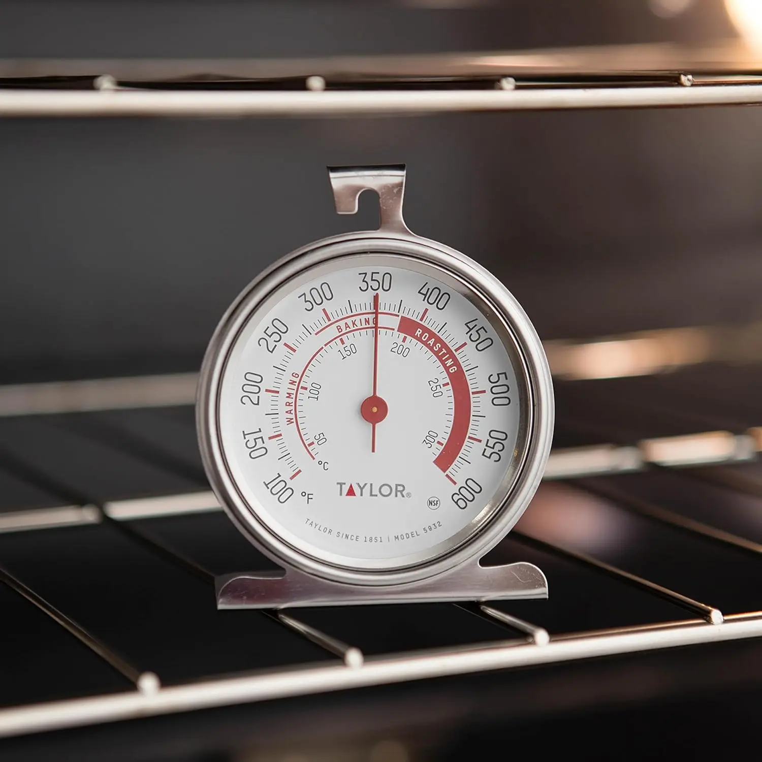 This Taylor stainless steel oven thermometer features a large, easy-to-read 3.25-inch dial with a red pointer, displaying temperatures from 100 to 600 degrees Fahrenheit, and is NSF certified for quality and durability, designed to either hang or stand inside your oven.