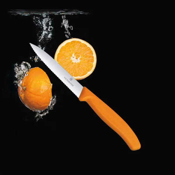 A close-up shows a Victorinox Swiss Classic 3.9-inch paring knife with a serrated blade and orange handle, perfect for precision cutting of fruits and vegetables in the kitchen.
