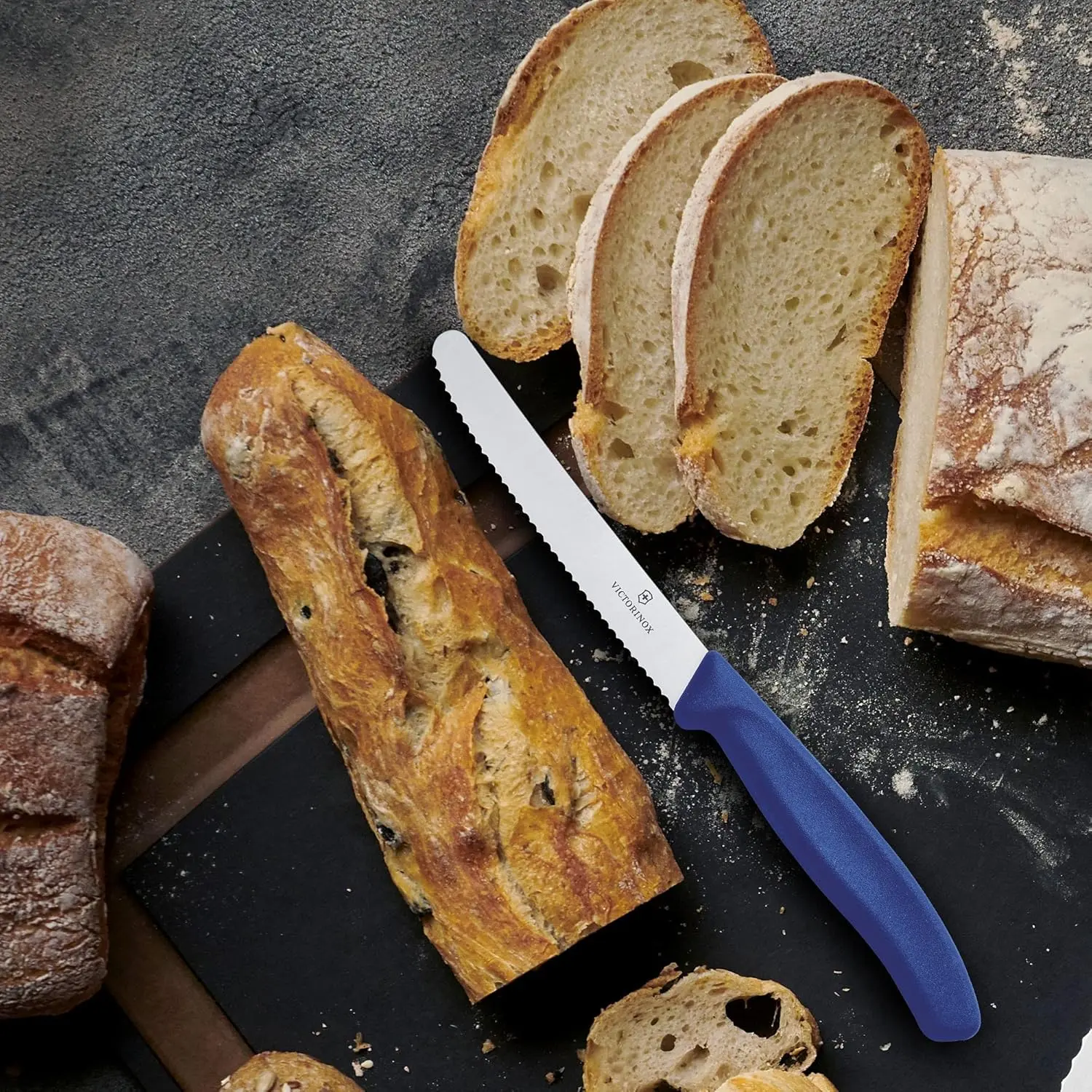 A blue-handled Victorinox Swiss Classic tomato knife with a wavy edge is displayed, highlighting its precision and sharpness for effortless slicing.